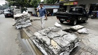 Lumpur dimasukkan ke karung untuk dibuang.