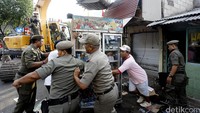 Warga mengevakuasi barang-barangnya. Sementara ekskavator telah disiapkan untuk melakukan pembongkaran.