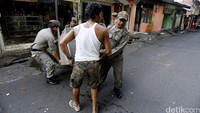 Seorang warga dibantu Satpol PP mengevakuasi barang-barang dari dalam bangunan yang akan dibongkar.