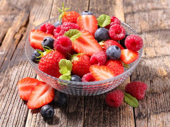 Heathy food for my baby. Pregnant woman holding a plate with fruits, studio isolated