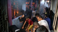 Warga dan petugas berusaha memadamkan api.