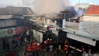 Warga dan petugas berusaha memadamkan api.