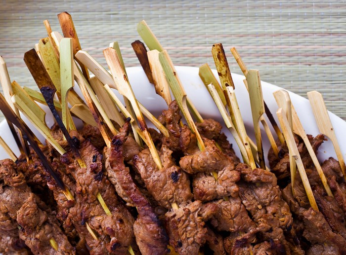 Grilled vegetable and meat skewers with addition of fresh herbs on a wooden rustic table