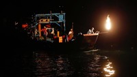 Mereka menggunakan nyala obor api dari karbit. Obor ini sebagai magnet untuk menarik ikan di malam hari (Tyrone Siu/Reuters)