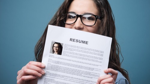 Young woman hiding behind her resume