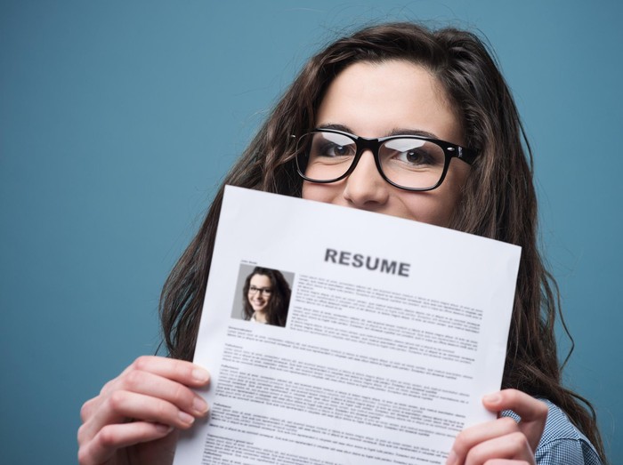 Young woman hiding behind her resume