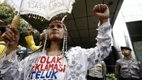 Seorang pendemo memakai baju dipenuhi koin dengan tulisan tolak reklamasi Teluk Jakarta. Ia juga membawa payung.