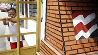 Seorang anak berdiri di depan gerbang yang telah digembok.