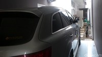 Sebuah mobil Audi SUV bernomor polisi B 18 JBM warna silver dan sepeda terparkir di garasi rumah.