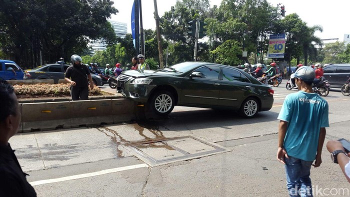 Bruuuk! Camry Hijau Ringsek Tabrak dan Nyangkut di Separator Busway
