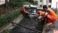 Pasukan oranye membersihkan sampah yang menyumbat selokan.