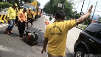 Petugas mengeraskan jalan yang baru saja ditambal.