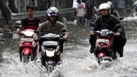 Beberapa pengendara sepeda motor menerobos banjir.