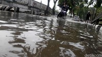 Pengendara sepeda motor menerobos banjir.