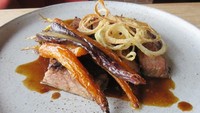 Daging diberi guyuran saus kecokelatan gurih. Lalu dihias dengan onion ring renyah dan wortel panggang madu.