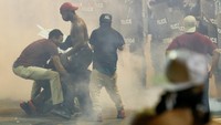 Polisi anti huru hara menembakan gas air mata ke ratusan orang yang mengejek mereka di sebuah hotel di pusat kota. REUTERS/Jason Miczek.