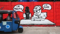 Warga melintas di depan mural bernada kritik sosial di bantaran Kali Opak, Penjaringan, Jakarta Utara. Kekuasaan, politik dan tata kota menjadi sorota. Ari Saputra/detikcom
