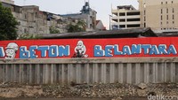 Pernyataan mural yang tegas Jakarta Beton Belantara memanjang di bantaran Kali Opak, Penjaringan.