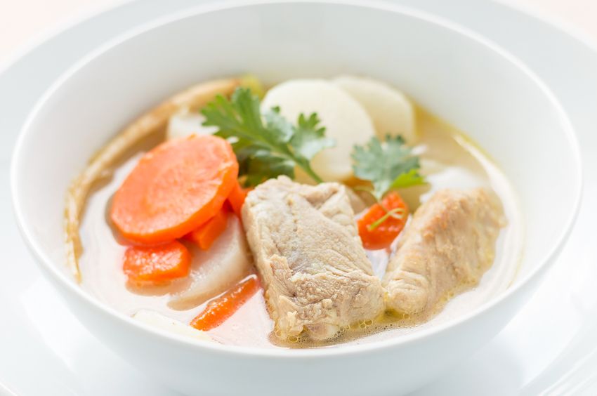 vegetable clear soup with wooden spoon on wooden table