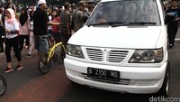 Mobil tersebut tampak didatangi petugas kepolisian karena melintas di antara ribuan orang yang sedang berolahraga.