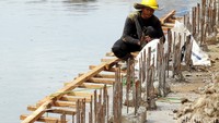 Seorang pekerja menyelesaikan pemasangan turap di salah satu sisi sungai.