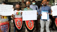 Mereka memakai pakaian khas Papua dan melakban mulut.
