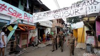 Suasana Bukit Duri sebelum ditertibkan. Tampak beberapa petugas melintas di bawah spanduk menolak penggusuran.