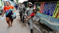 Salah satu personel Satpol PP nampak menggendong seorang balita di tengah pembongkaran bangunan di bantaran kali Ciliwung, Bukit Duri, Jakarta Selatan, Rabu (28/9/2016).
