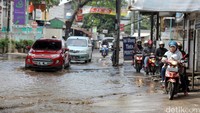 Beberapa pengendara sepeda motor berusaha menghindari banjir.