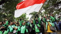 Massa yang mengenakan jaket hijau ini membawa bendera merah putih.
