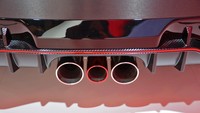 Lip spoiler depan serat karbon dengan aksen merah menambah kesan agresif pada mobil ini.