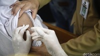 Petugas kesehatan nampak sedang menyuntik vaksin kepada seorang anak.