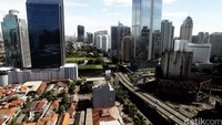Gedung-gedung pencakar langit menghimpit pemukiman warga secara vertikal.