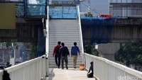 Warga yang akan menyeberang dialihkan dari JPO baru ke separuh JPO yang lama.