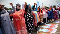 Para buruh perempuan mengepalkan tangan bersama.