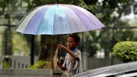 Seorang anak menawarkan jasa ojek payung.