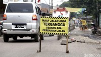 Papan peringatan perbaikan terpampang di jalan tersebut.