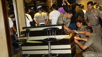 Petugas memasang garis warna kuning pada properti dalam ruangan seperti meja dan kursi pengunjung.