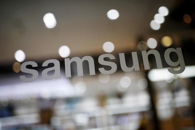 A man walks behind a logo of Samsung Electronics at the company's headquarters in Seoul April 30, 2010.  REUTERS/Jo Yong-Hak/File Photo