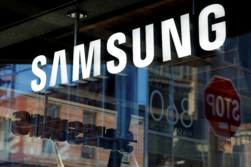 A man walks behind a logo of Samsung Electronics at the company's headquarters in Seoul April 30, 2010.  REUTERS/Jo Yong-Hak/File Photo