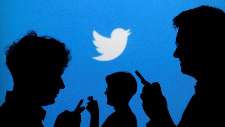 People holding mobile phones are silhouetted against a backdrop projected with the Twitter logo in this illustration picture taken in  Warsaw September 27, 2013.   REUTERS/Kacper Pempel/Illustration/File Photo