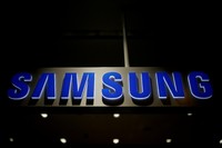 A man walks behind a logo of Samsung Electronics at the companys headquarters in Seoul April 30, 2010.  REUTERS/Jo Yong-Hak/File Photo