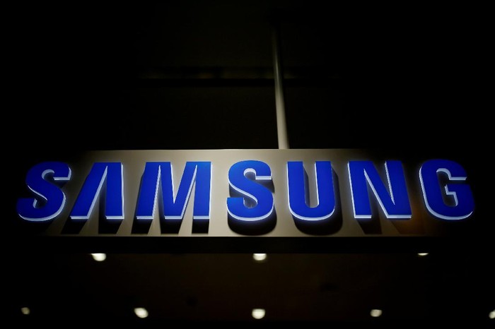 A man walks behind a logo of Samsung Electronics at the companys headquarters in Seoul April 30, 2010.  REUTERS/Jo Yong-Hak/File Photo