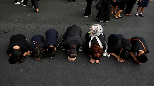 Warga berlutut ke arah Grand Palace yang menjadi tempat persemayaman jenazah Raja Bhumibol