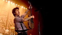 Aksi membanting alat musik juga dilakukan Billie Joe Armstrong yang marah karena diingatkan waktu penampilannya sebentar lagi. Foto: Kevin Winter/Getty Images