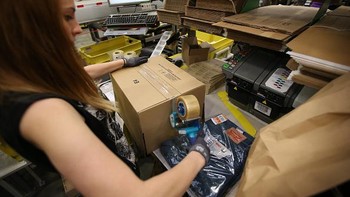 Seorang pegawai di gudang Amazon mengemas barang yang sudah dipesan oleh konsumen. Foto: Getty Images