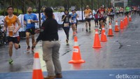 Petugas mengatur lintasan untuk pelari.