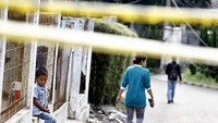 Seorang bocah duduk di pagar rumah sambil melihat bangunan Pizza Hut Delivery (PHD) yang telah rata dengan tanah.