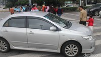 Seorang pengendara mobil terlihat menerobos saat pengguna jalan melewati zebra cross.