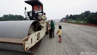 Beberapa anak bermain di sekitar alat berat di lokasi proyek Tol Cijago.